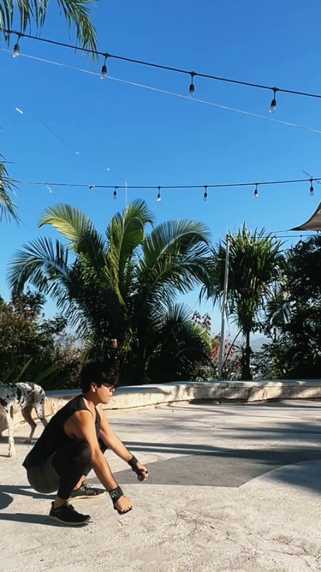 Mau Lemus in a deep squat on a terrace under palm trees