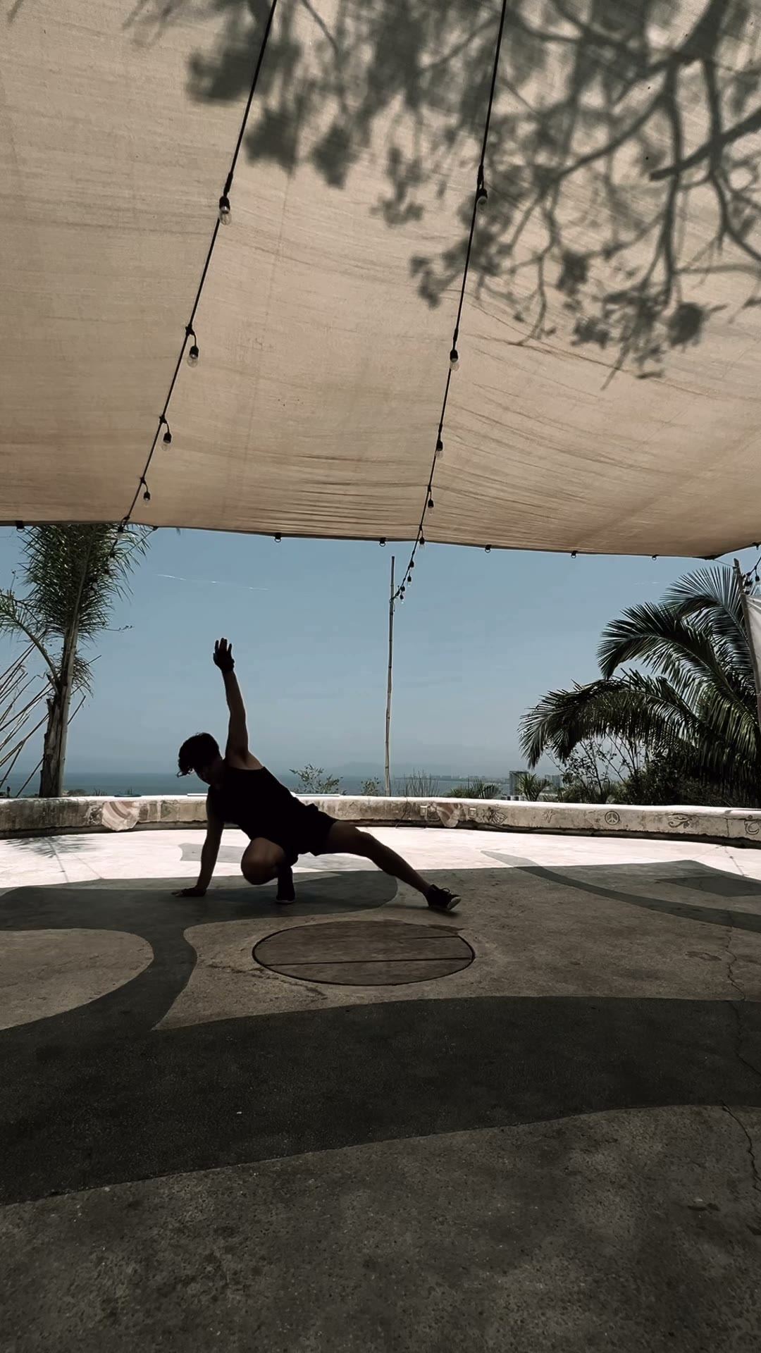 Side reach with the arm high, silhouetted against the ocean